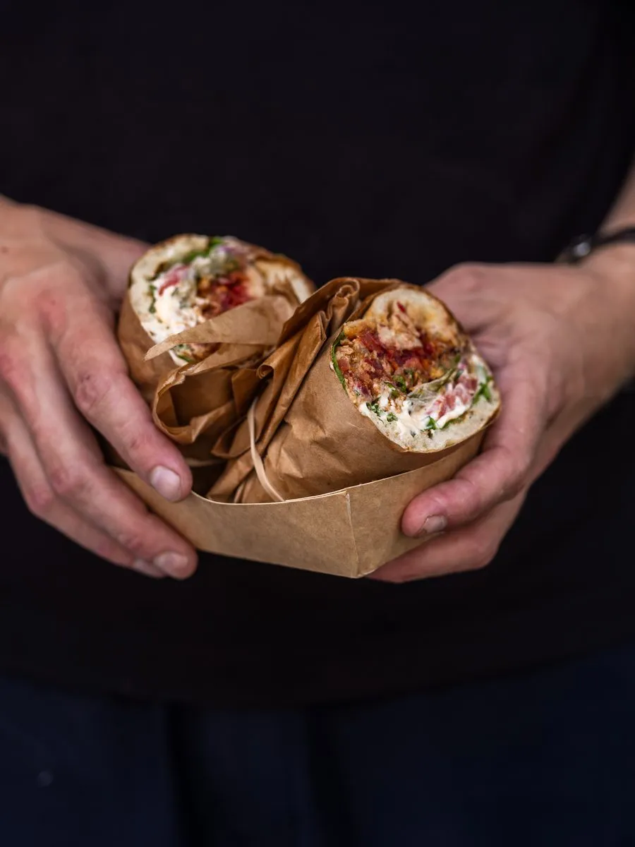 Två mackor i smörpapper räcks fram från foodtrucken