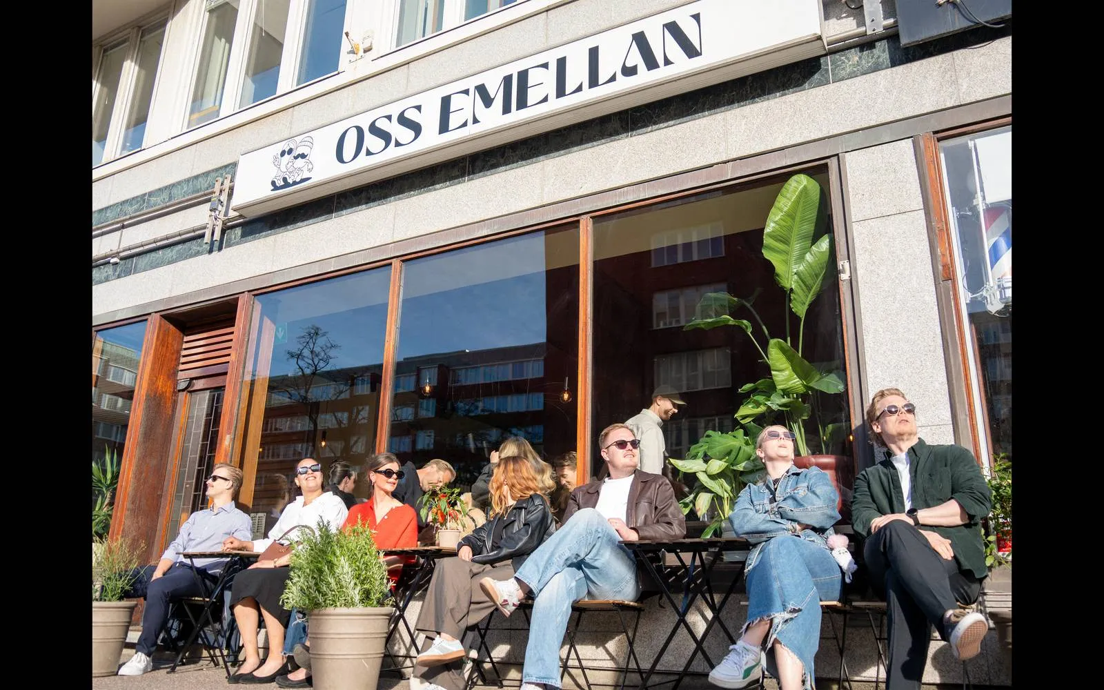 Gäster som sitter i solen på uteserveringen utanför Oss Emellan på Karl Johansgatan